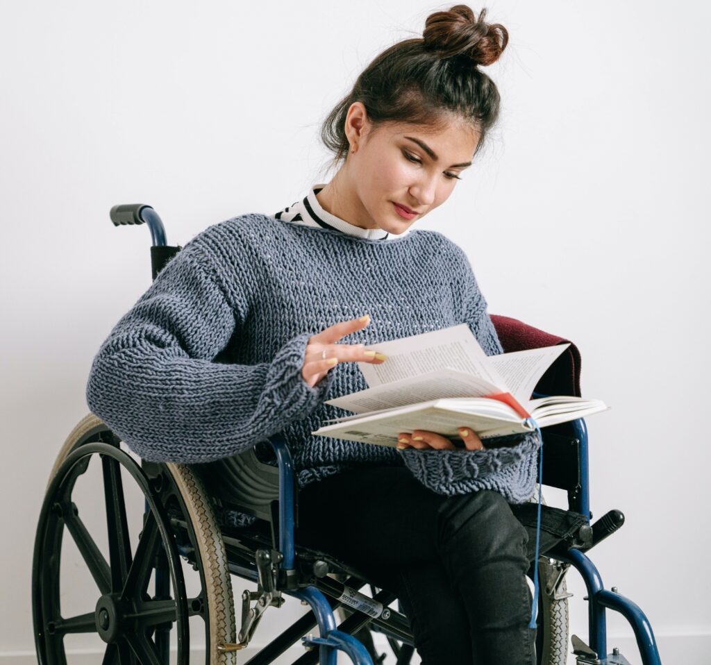 Une femme en fauteuil rouant feuillette un livre